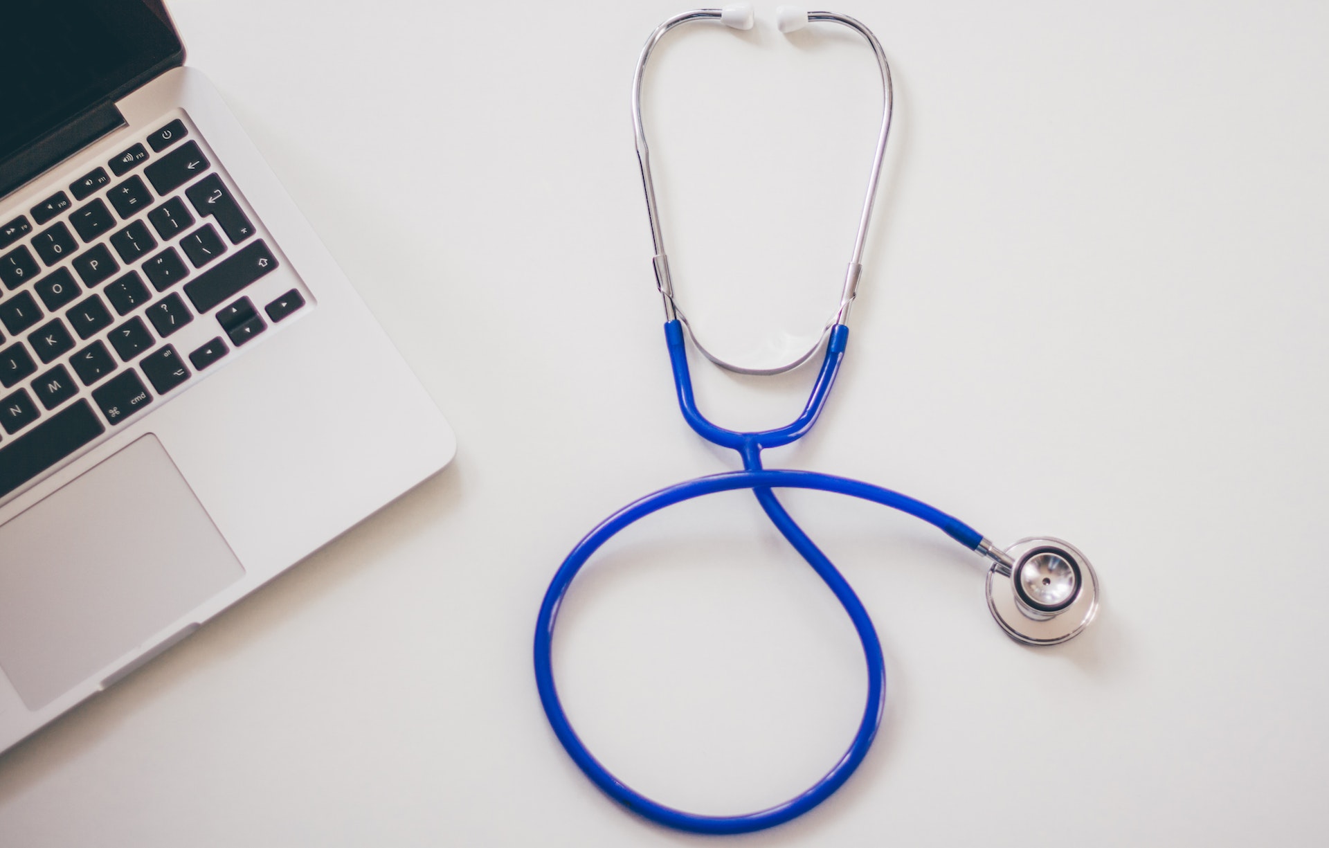 A stethoscope beside a laptop computer.