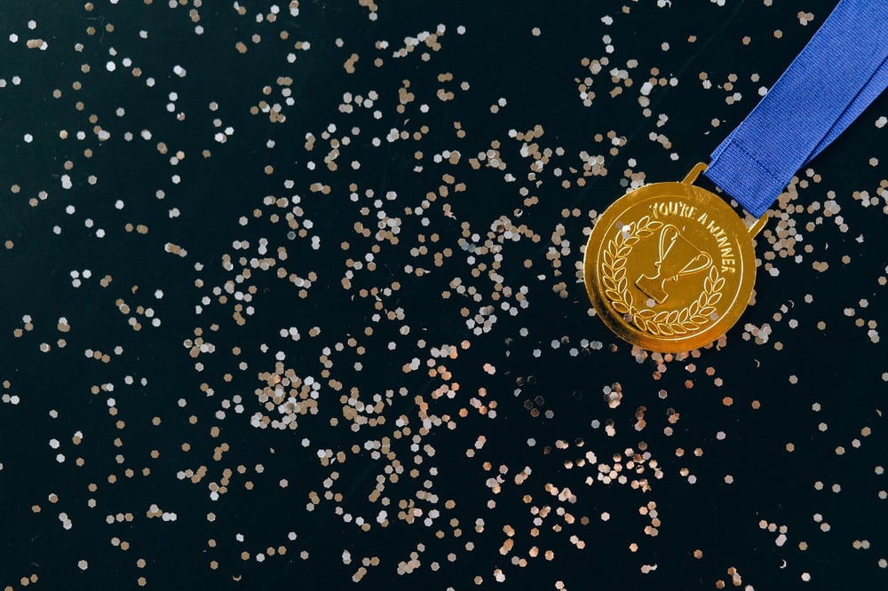 A gold medal on a confetti-covered background reads "You're a winner.""