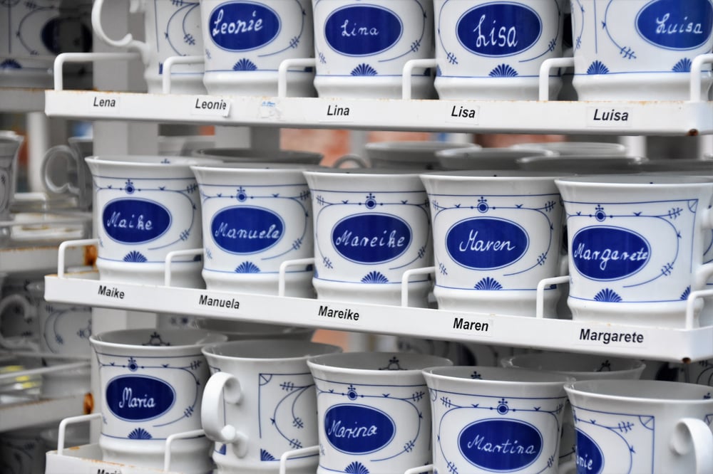 A rack of souvenir cups with different names on them.