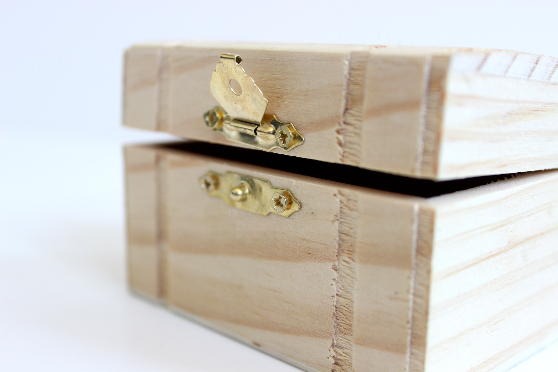 A small wooden box with the latch open and top slightly cracked.