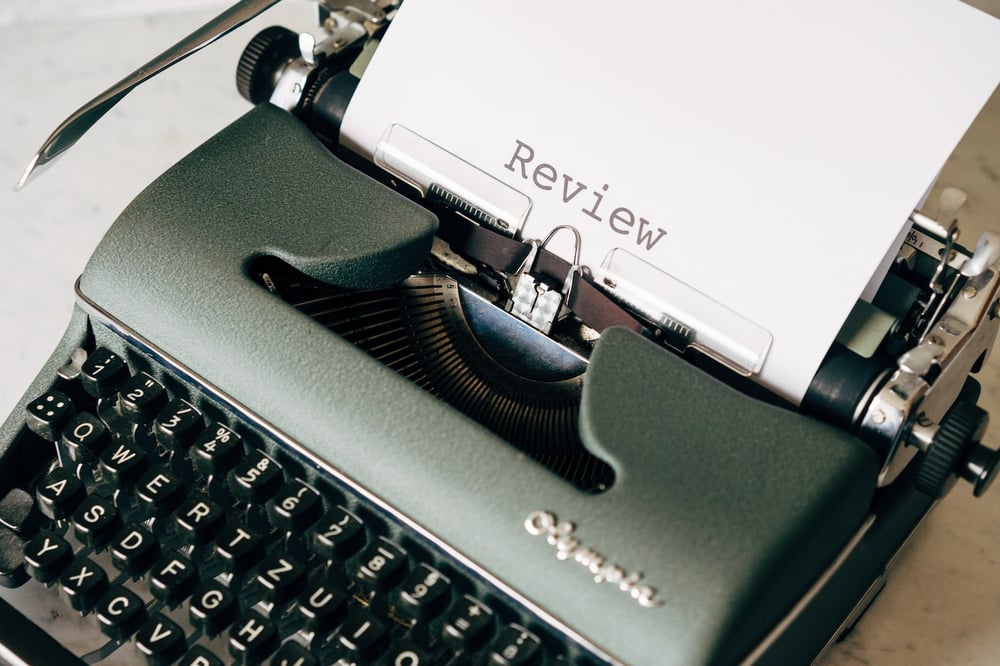 A vintage typewriter with a sheet of paper reading "Review" in it.