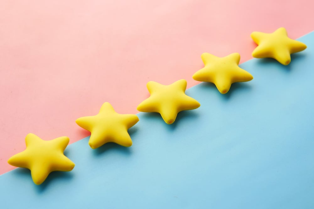 Five gold stars on a pink and blue background.