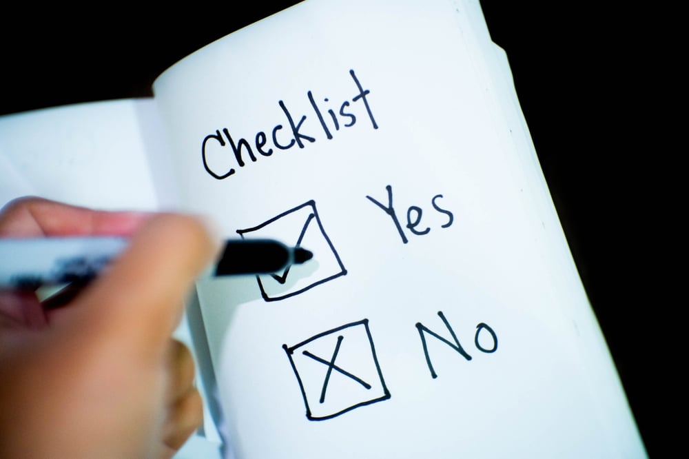 A hand holding a Sharpie checks a box for "yes" on a checklist with options for "yes" and "no."