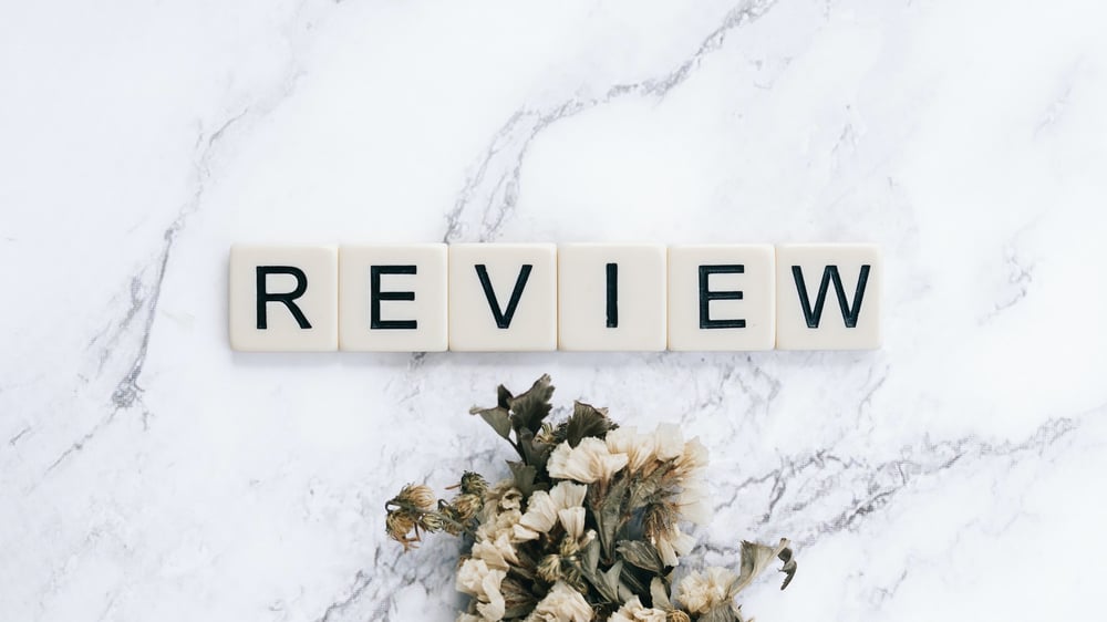 Scrabble tiles on a marble background read "REVIEW."