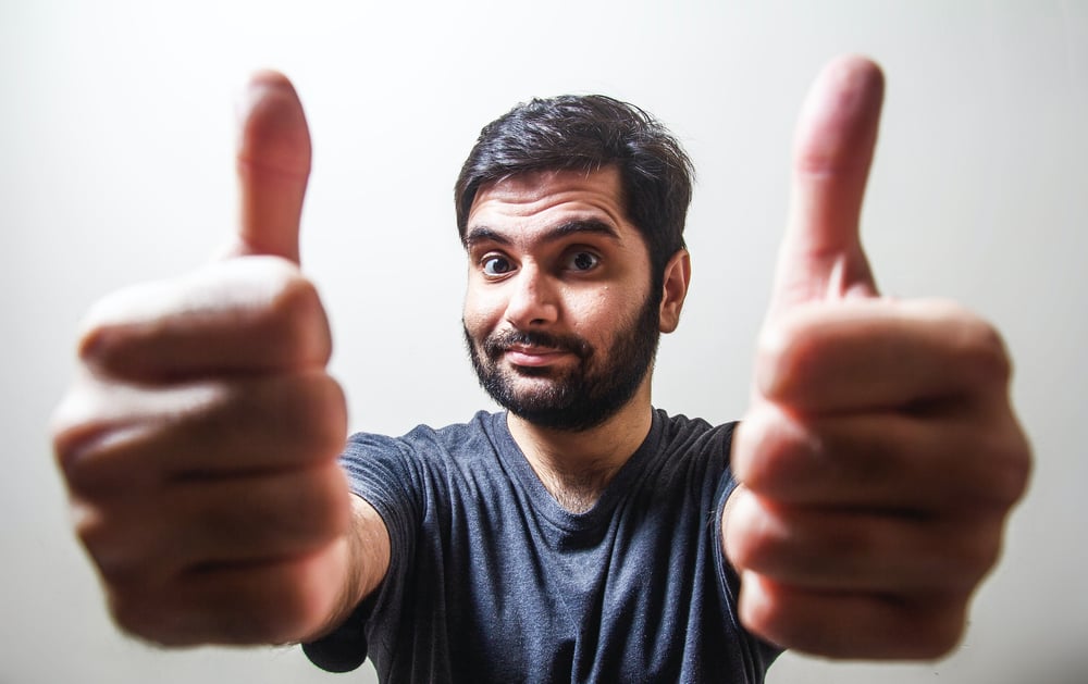 A person with a short beard gives two thumbs up.