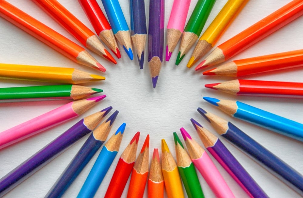The points of different colored pencils come together in the shape of a heart.