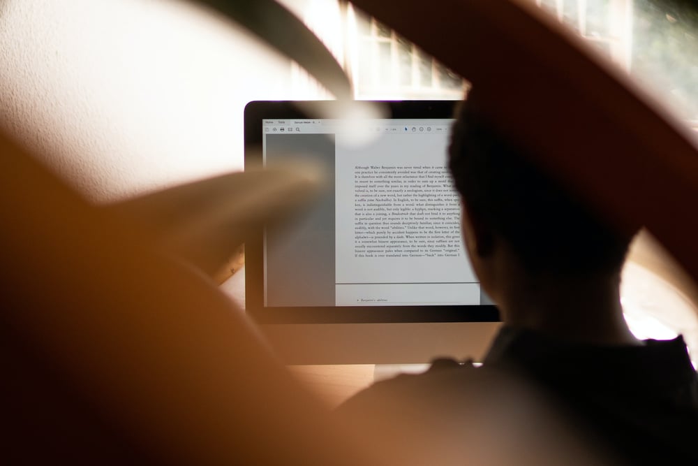 Blurry, over-the-shoulder view of a beta reader looking at a document on a computer screen.