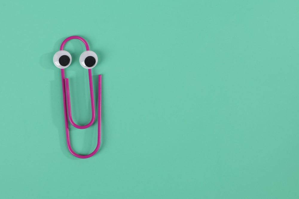 A purple paperclip with googly eyes on a teal background.
