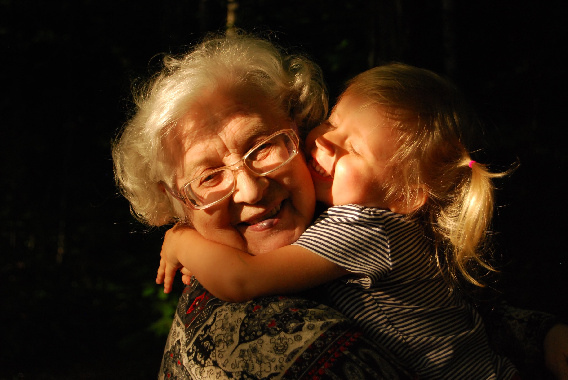 A smiling grandmother holds her toddler granddaughter.