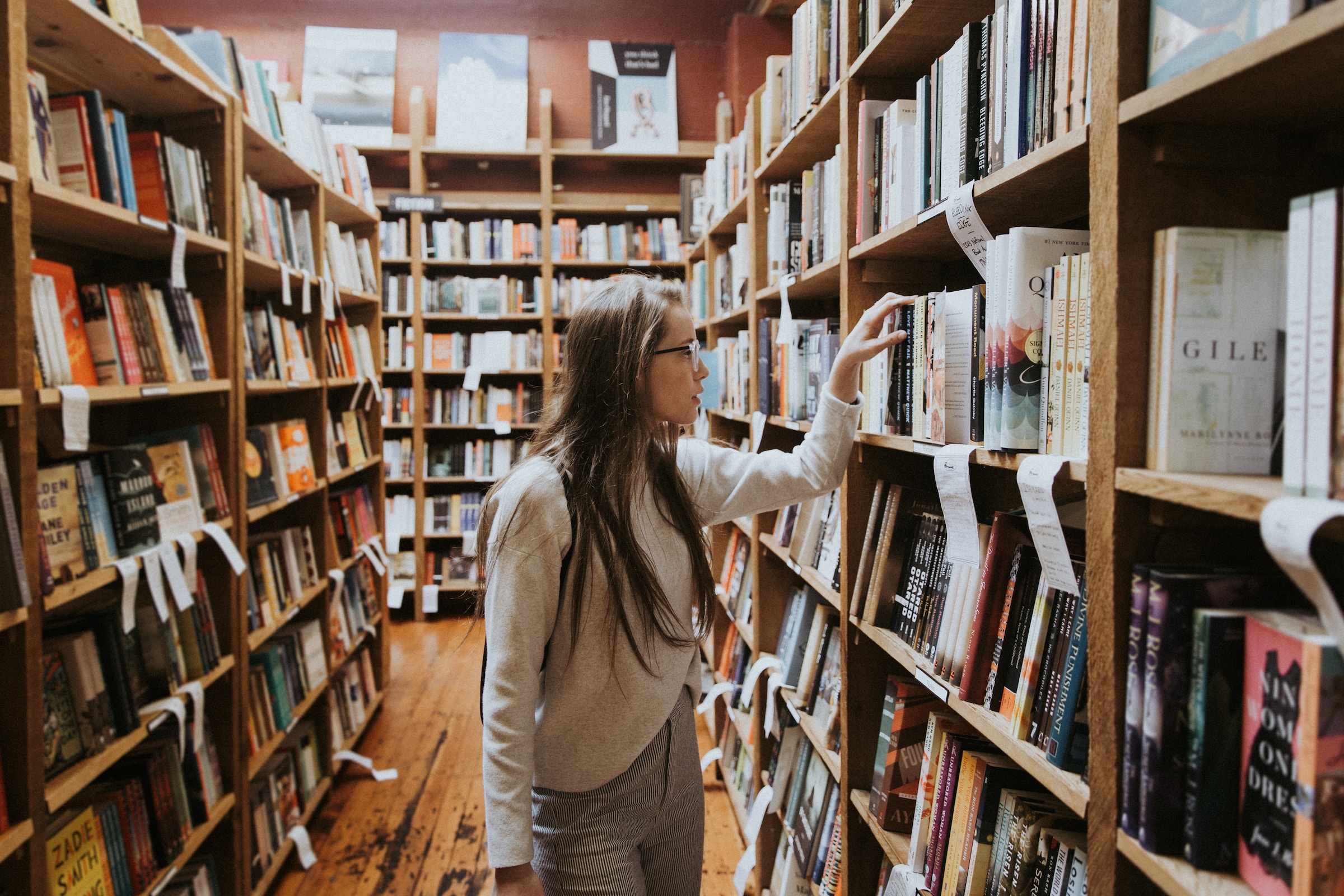 An adult browses the shelves of a bookshop.