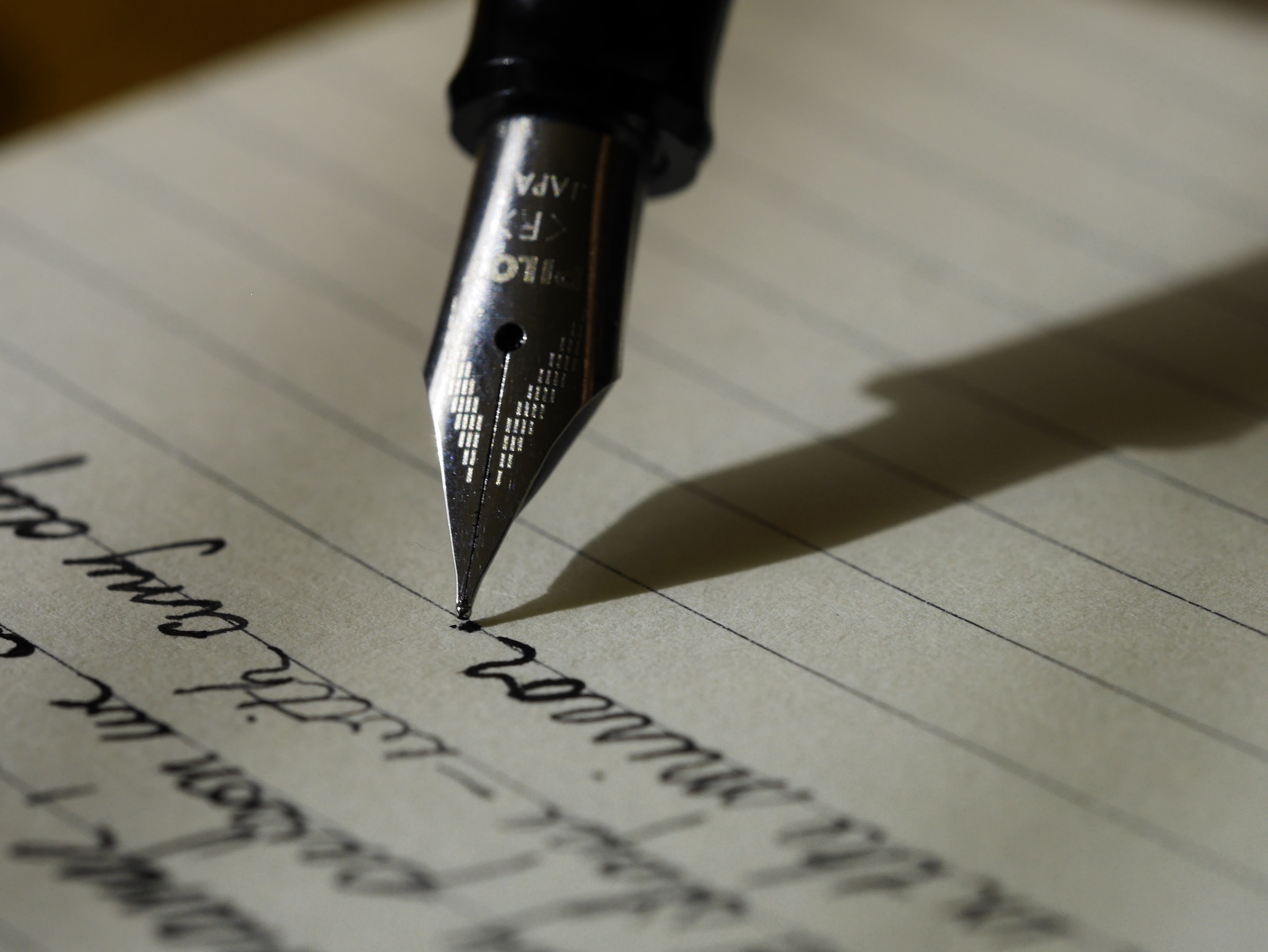 A fountain pen writes on a lined sheet of paper.