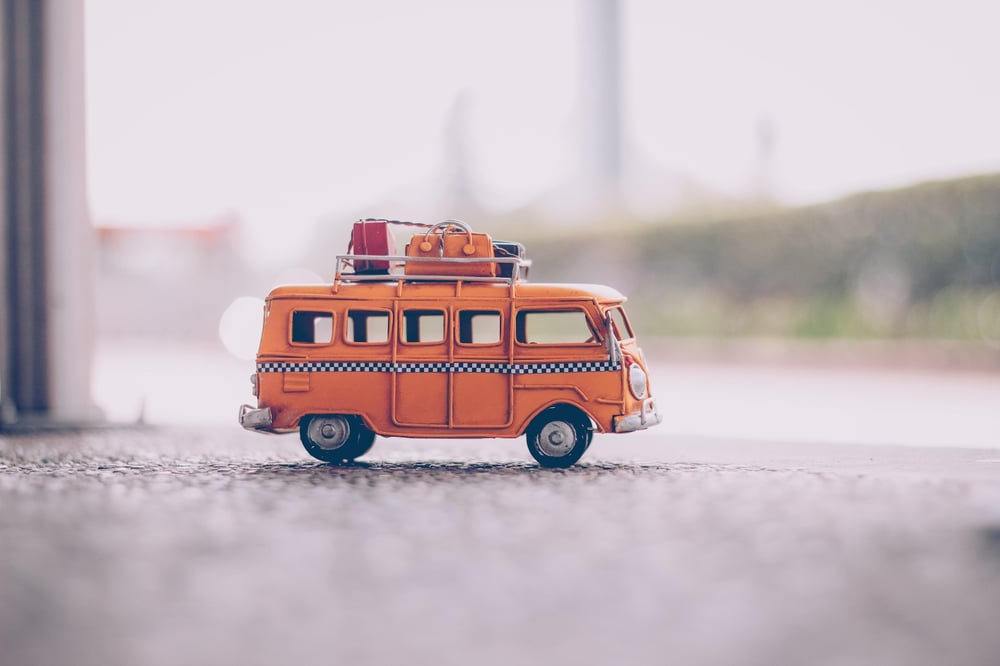 A toy bus with luggage on the roof.