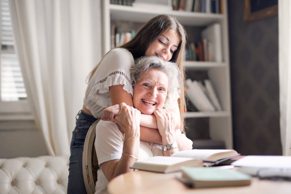 A young girl hugs her grandmother.