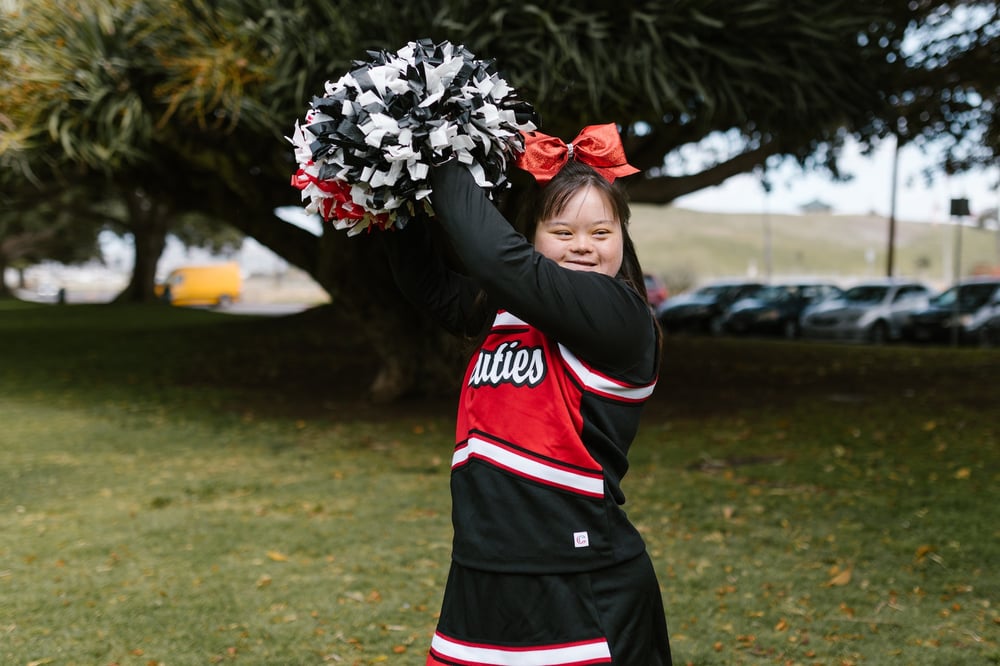 A cheerleader waves pom-poms.