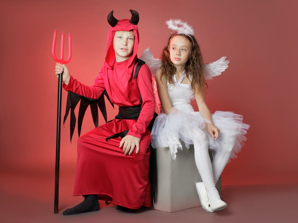 Children dressed in devil and angel costumes.