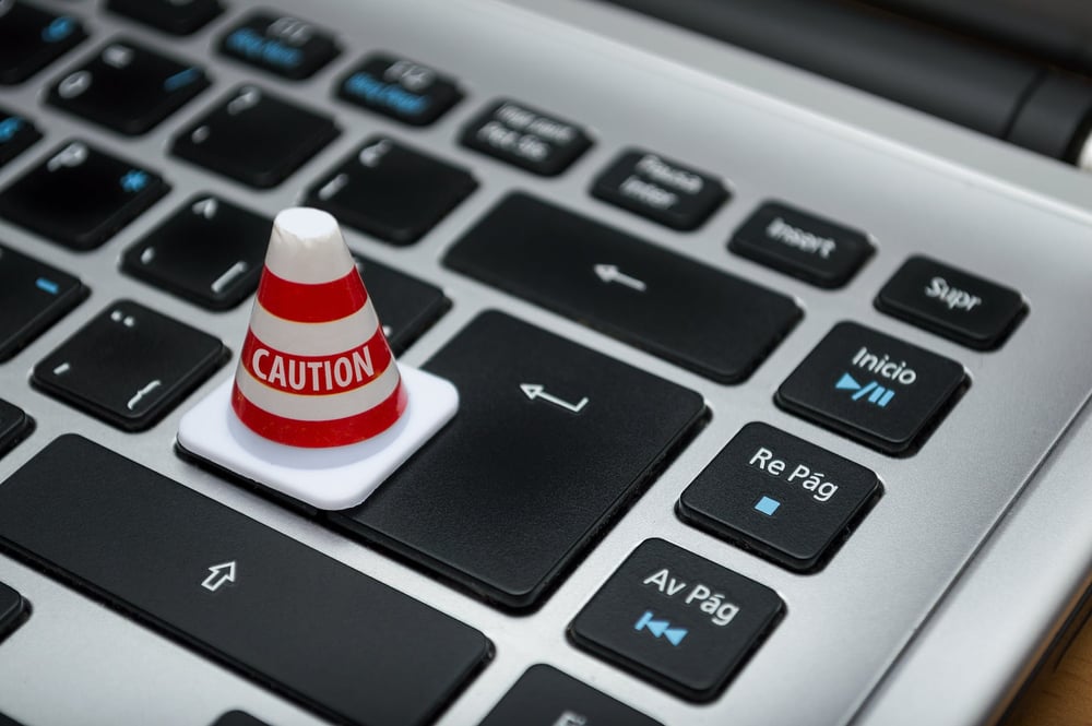 A tiny "caution" traffic cone on a computer keyboard.