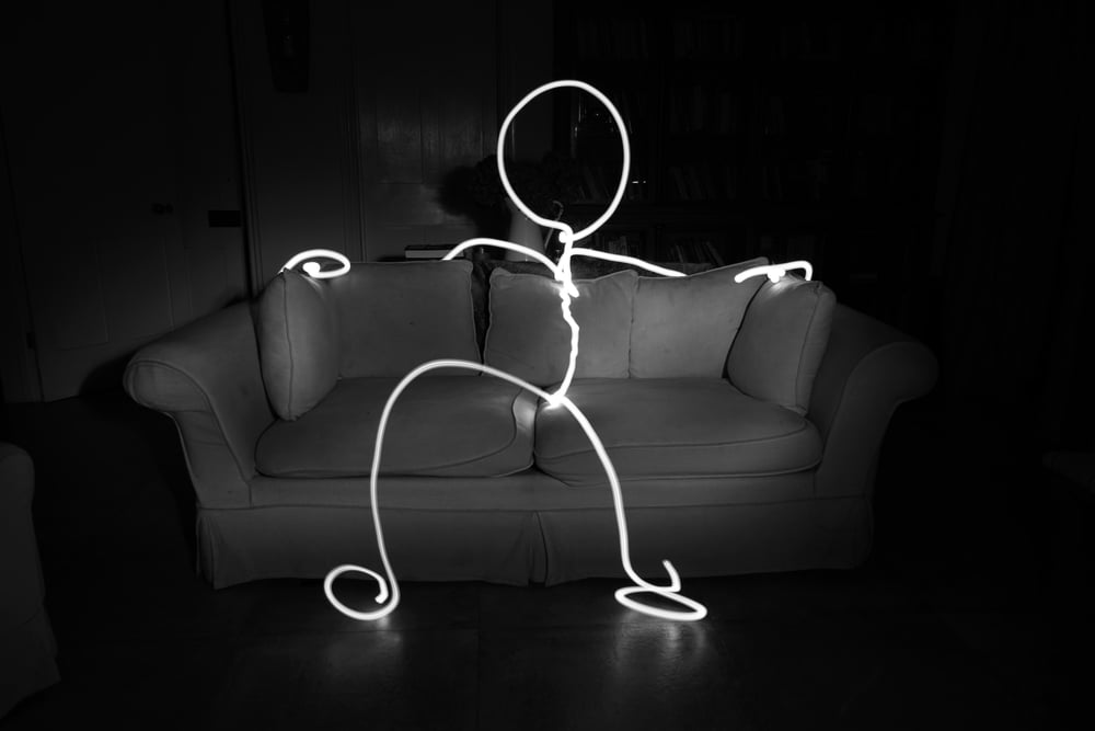 A glowing stick figure sits on a couch.