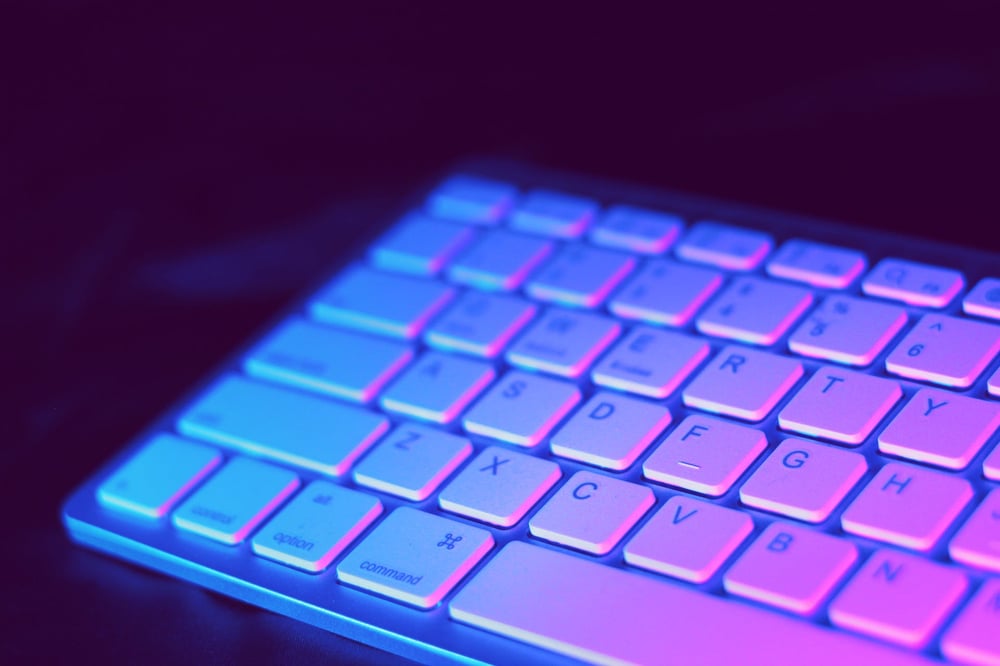 A keyboard with a purple glow shining on it.