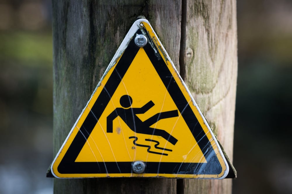 A yellow warning sign depicting a person slipping on water.