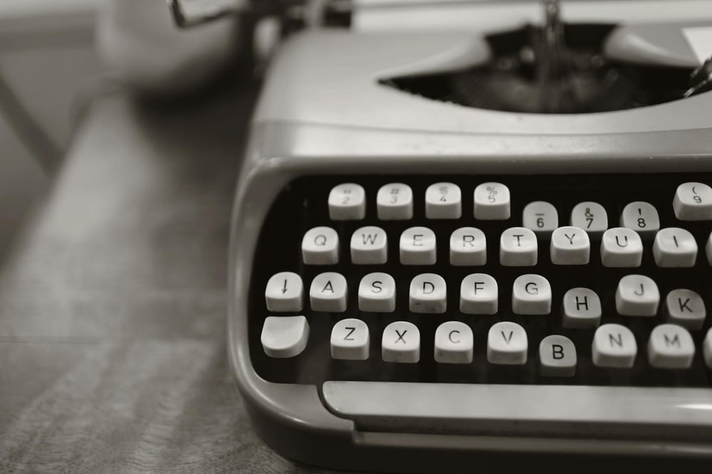 A gray vintage typewriter with some keys pushed down.