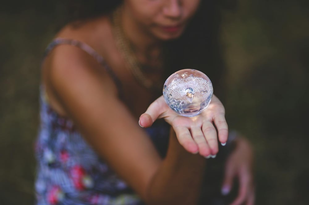 A person holds out a small crystal ball on the palm of their hand.