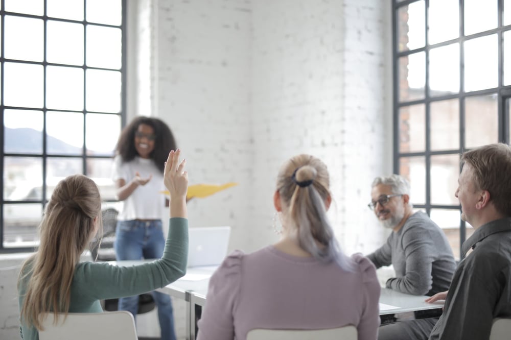 A person raises their hand in a meeting.