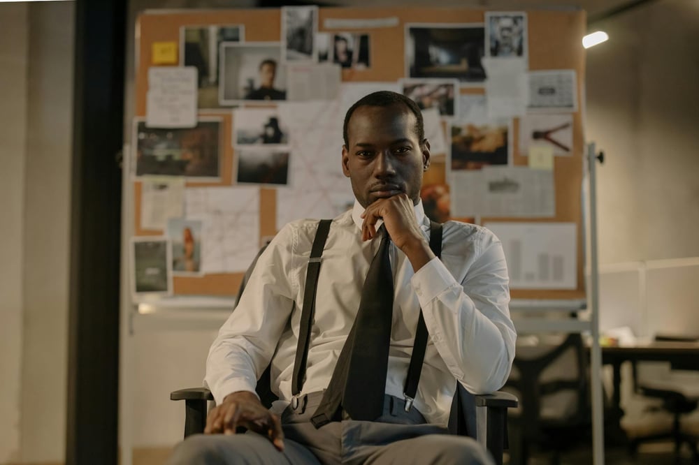 A detectives sits in front of an evidence board.