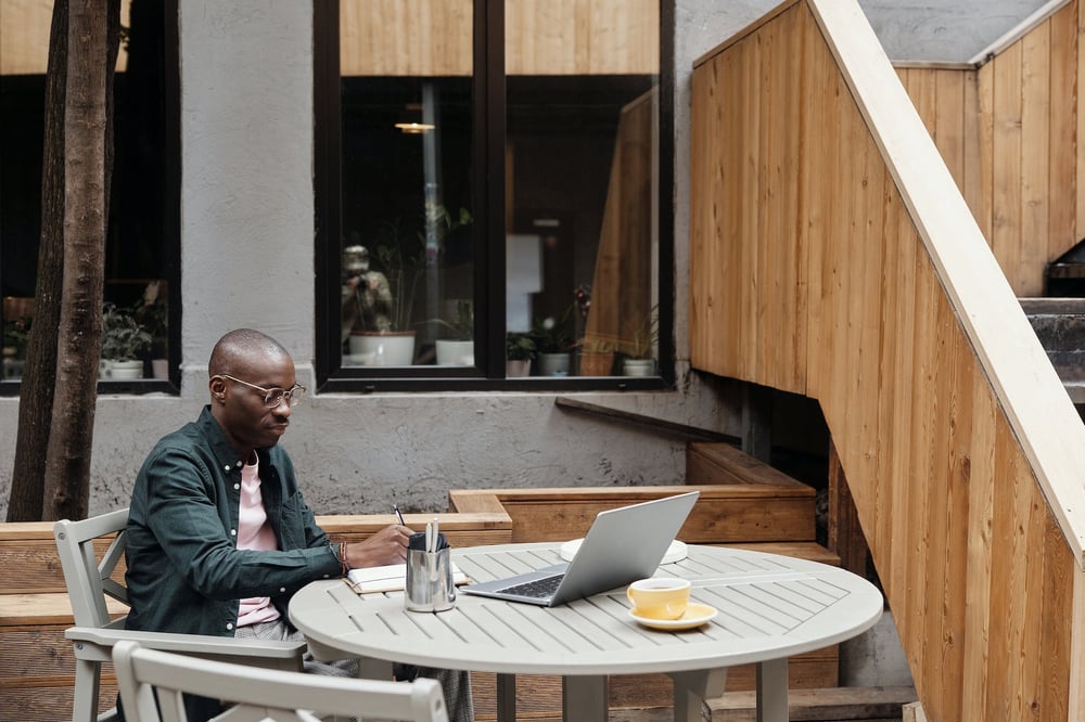 A person writes in a notebook at a cafe table.