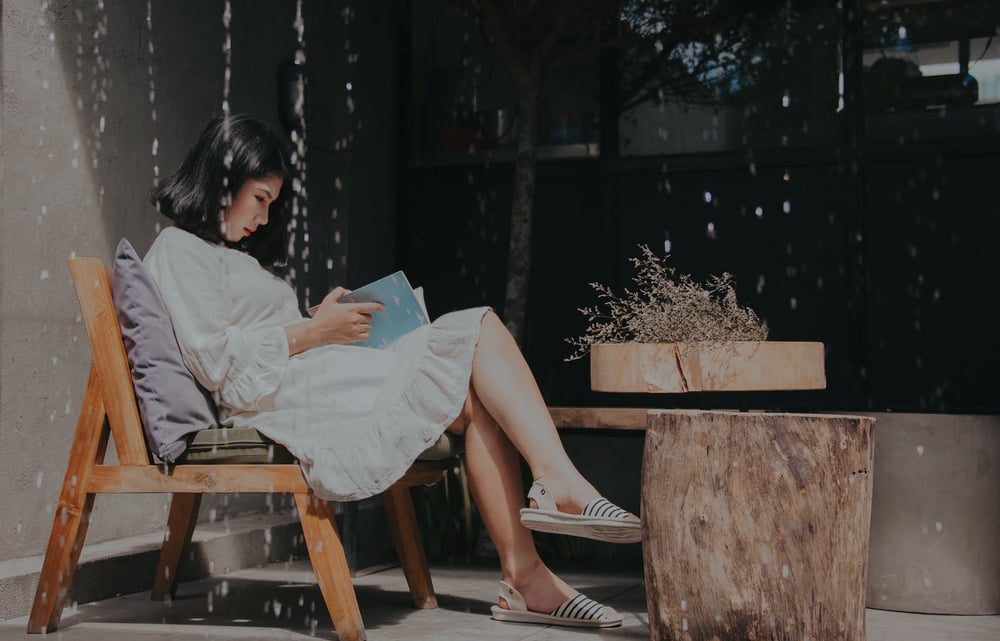 A person sits in a chair reading a book.