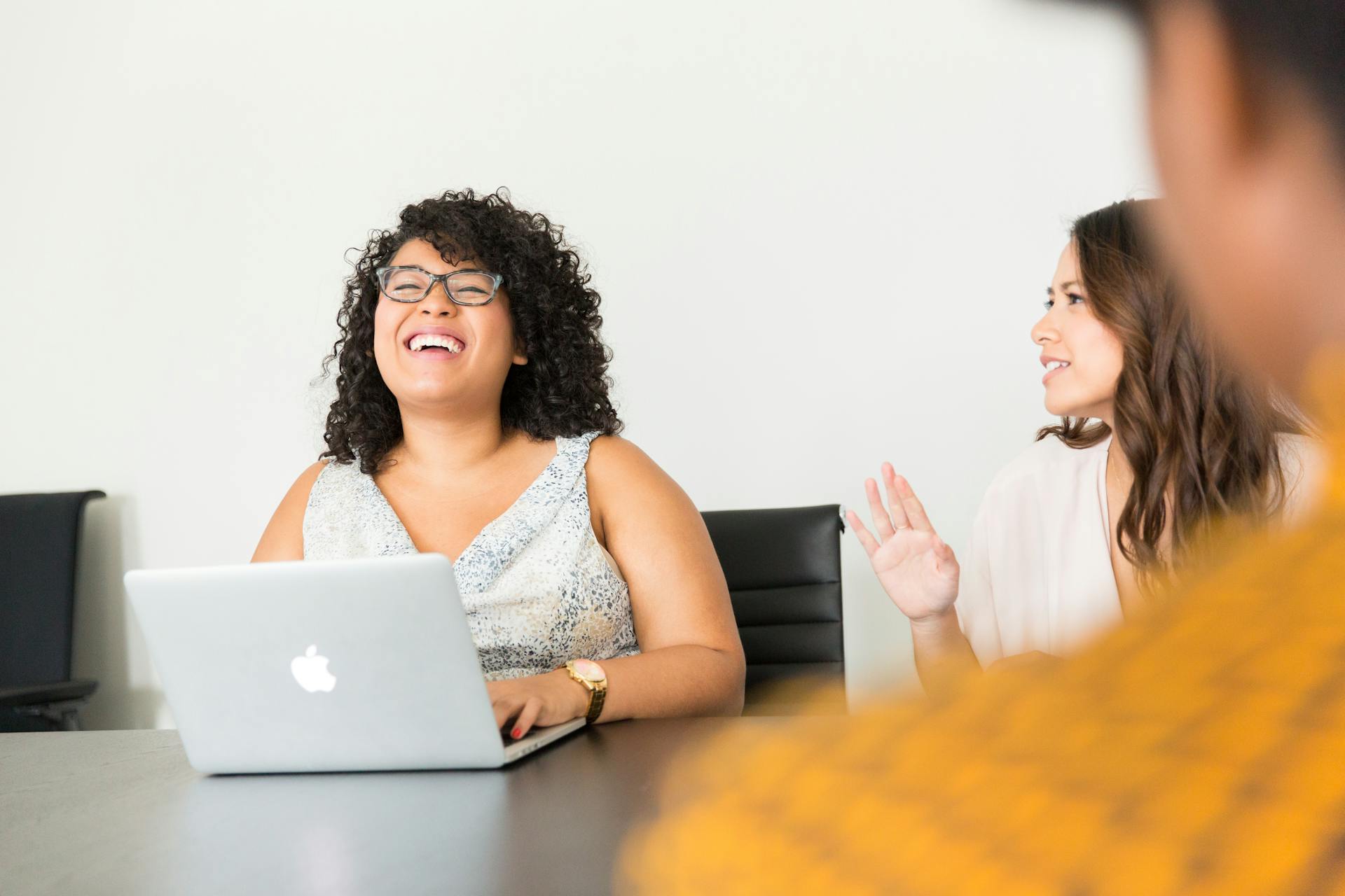 A person sitting in front of a computer laughs as they hear feedback from the person next to them.