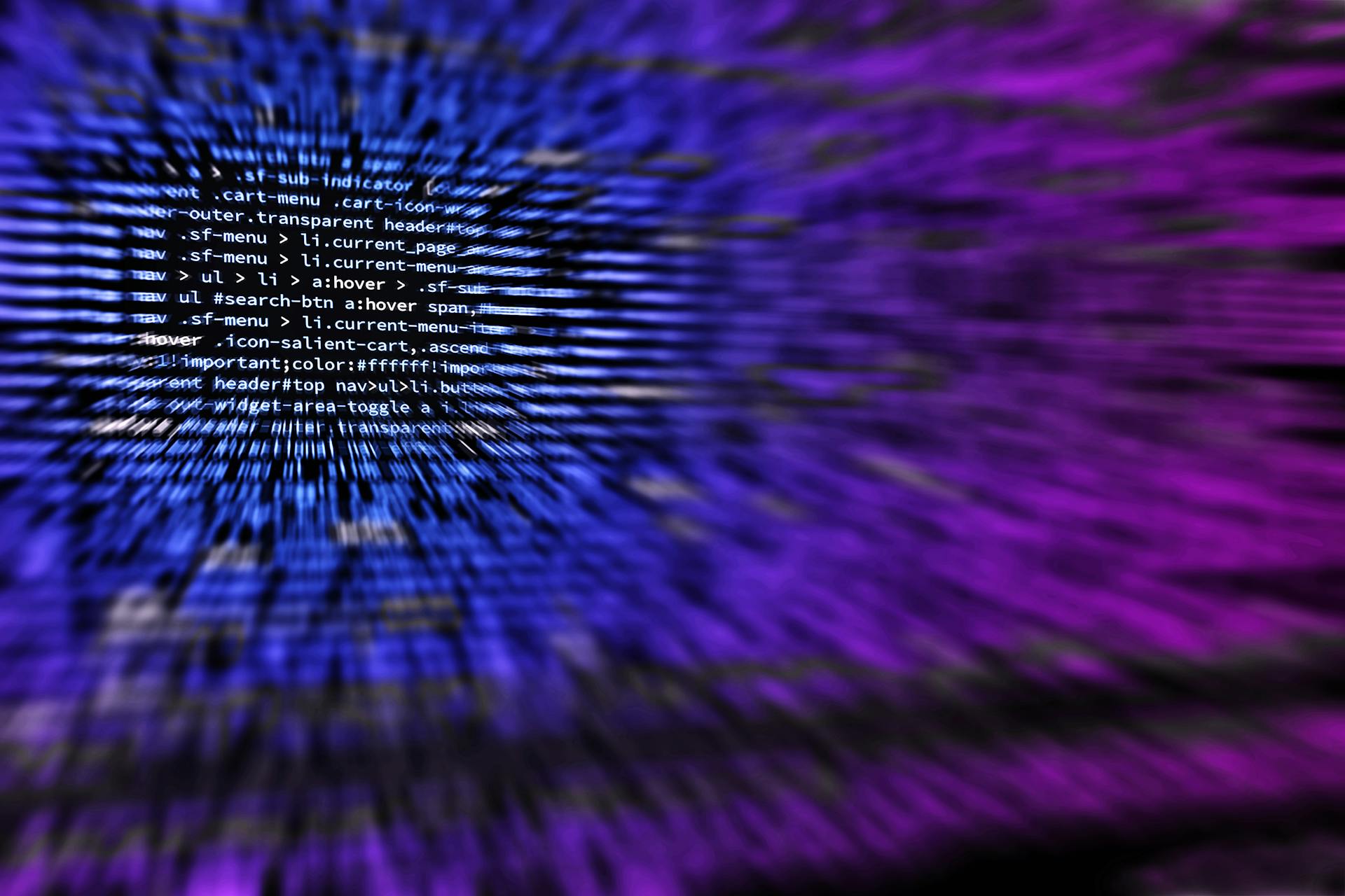 White computer code on a black screen blurs at the edges, creating streaks of blue and purple.