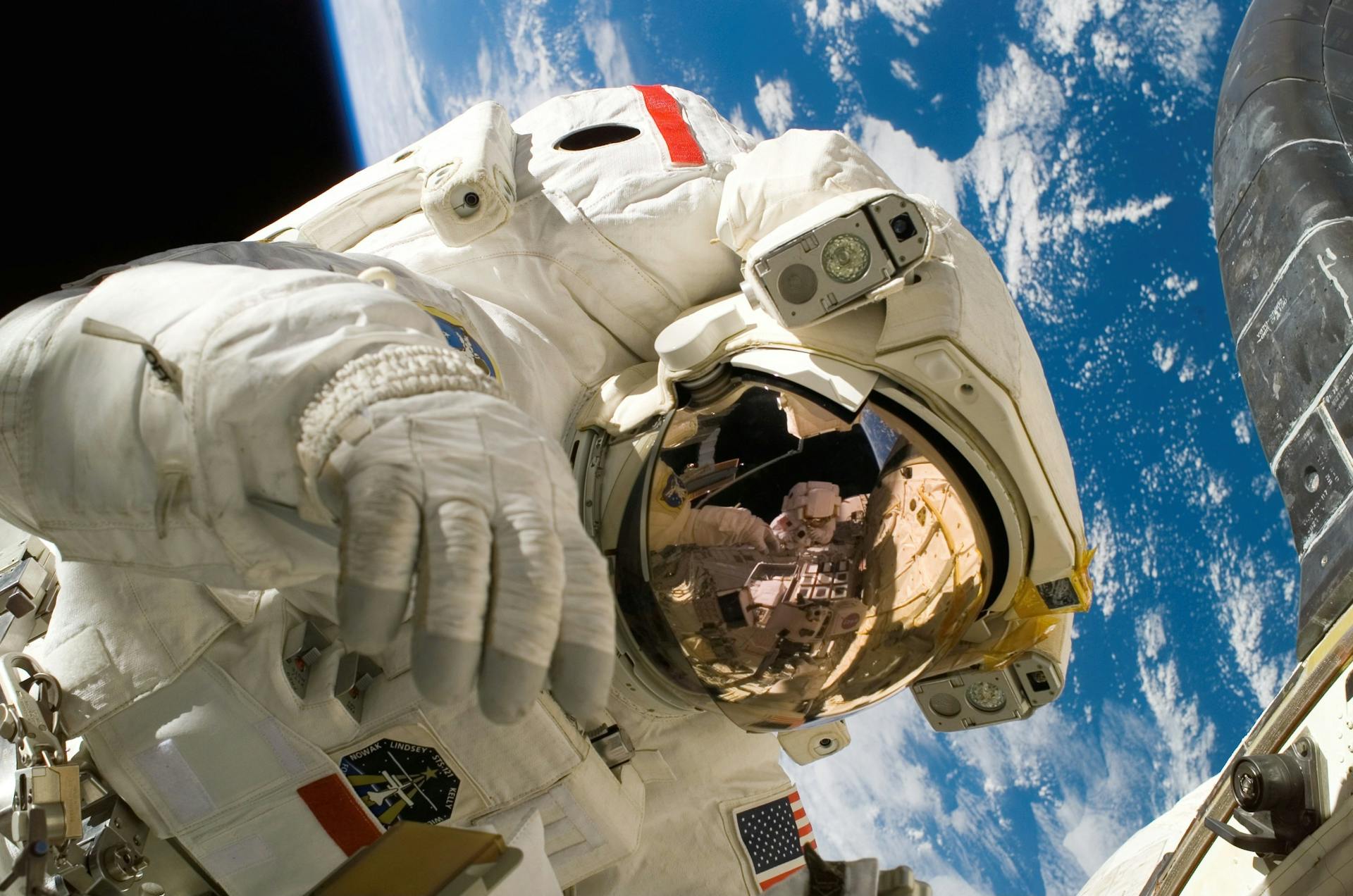 An astronaut works outside the shuttle with the earth in the background.e