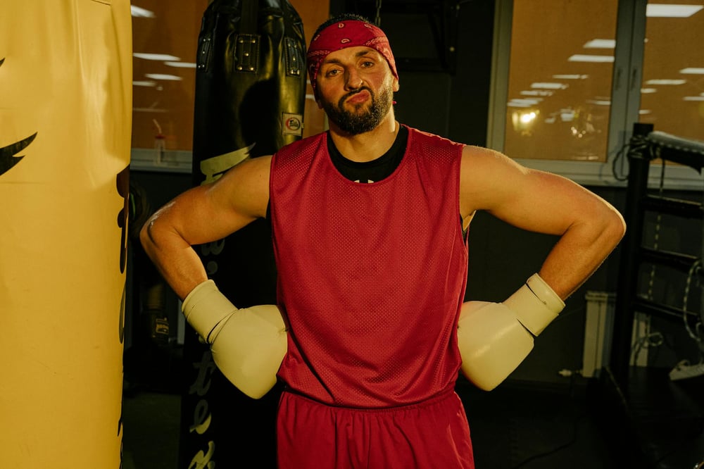 A person wearing boxing gloves stands with their hands on their hips.