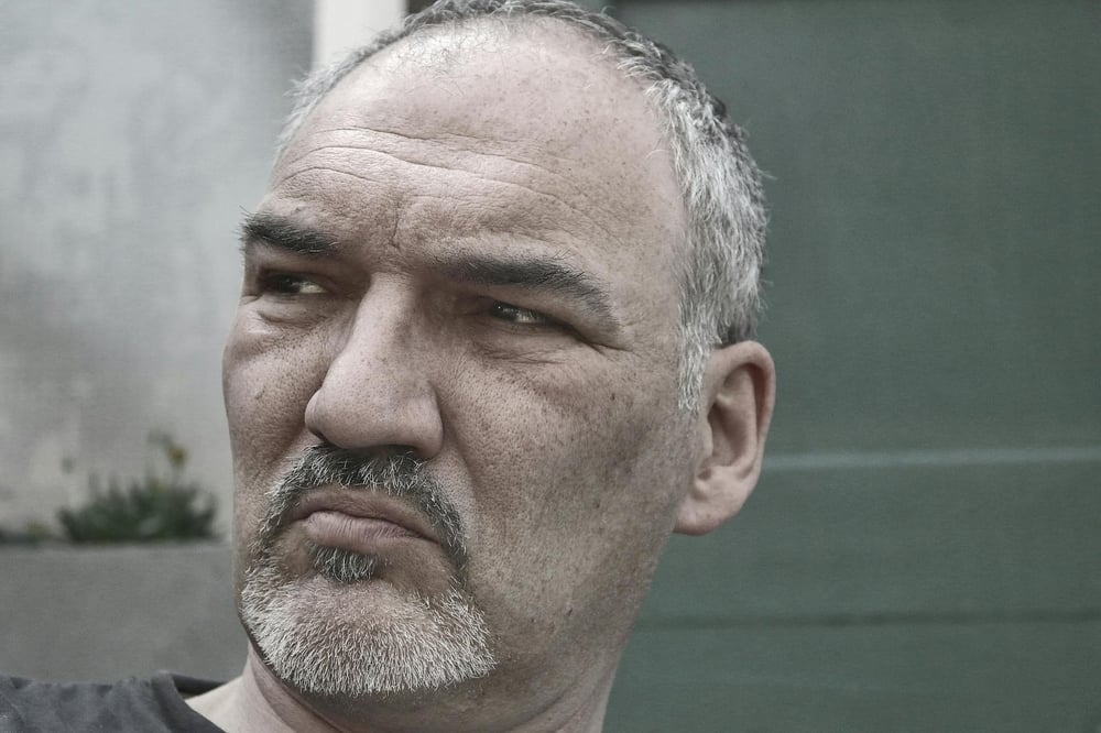 An irritated person with a goatee looks off to the side.