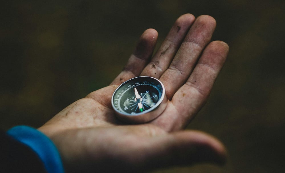 A dirty hand holds a compass.