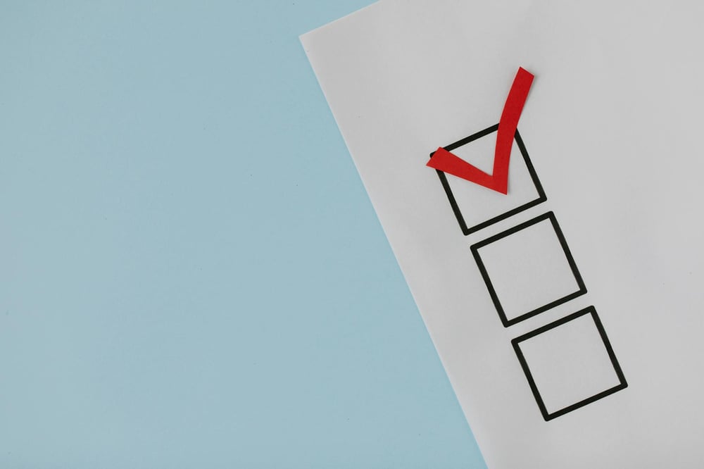 Against a blue background, a white sheet of paper has a column of three check boxes. A red checkmark is in the top box.