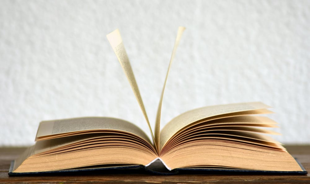 A book sits on a table with its pages fanned open.