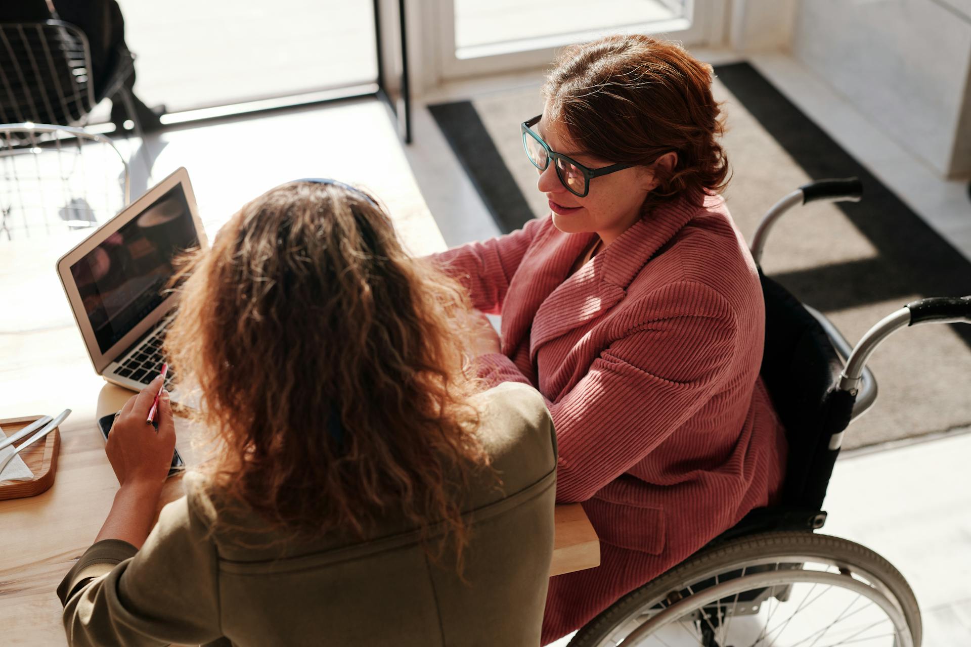 Two people sit and have a conversation in front of an open laptop.