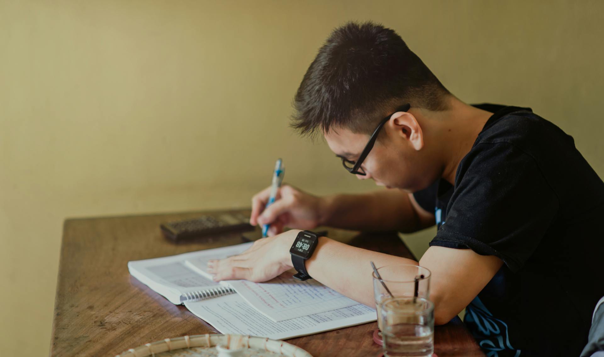 A person studies at a narrow wooden table.