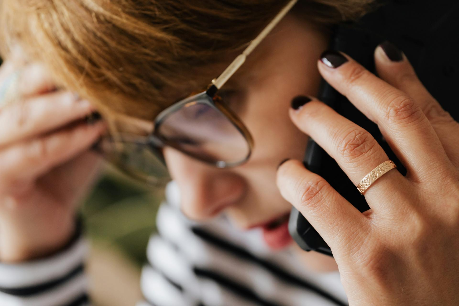 Close-up of a stressed person in a striped shirt talking on the phone.