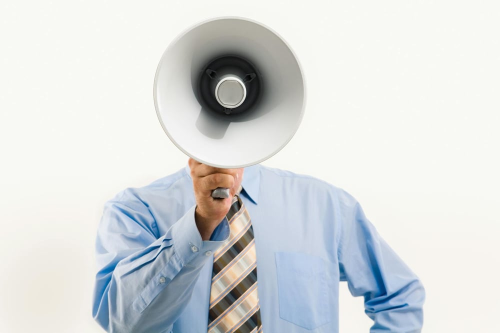 A person holds a bullhorn out in front of their face.