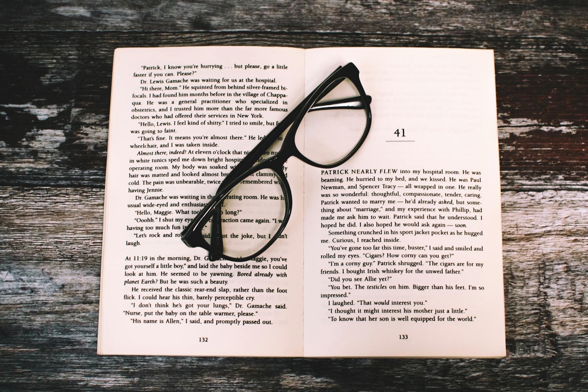 Black-framed glasses sit on the pages of an open book.