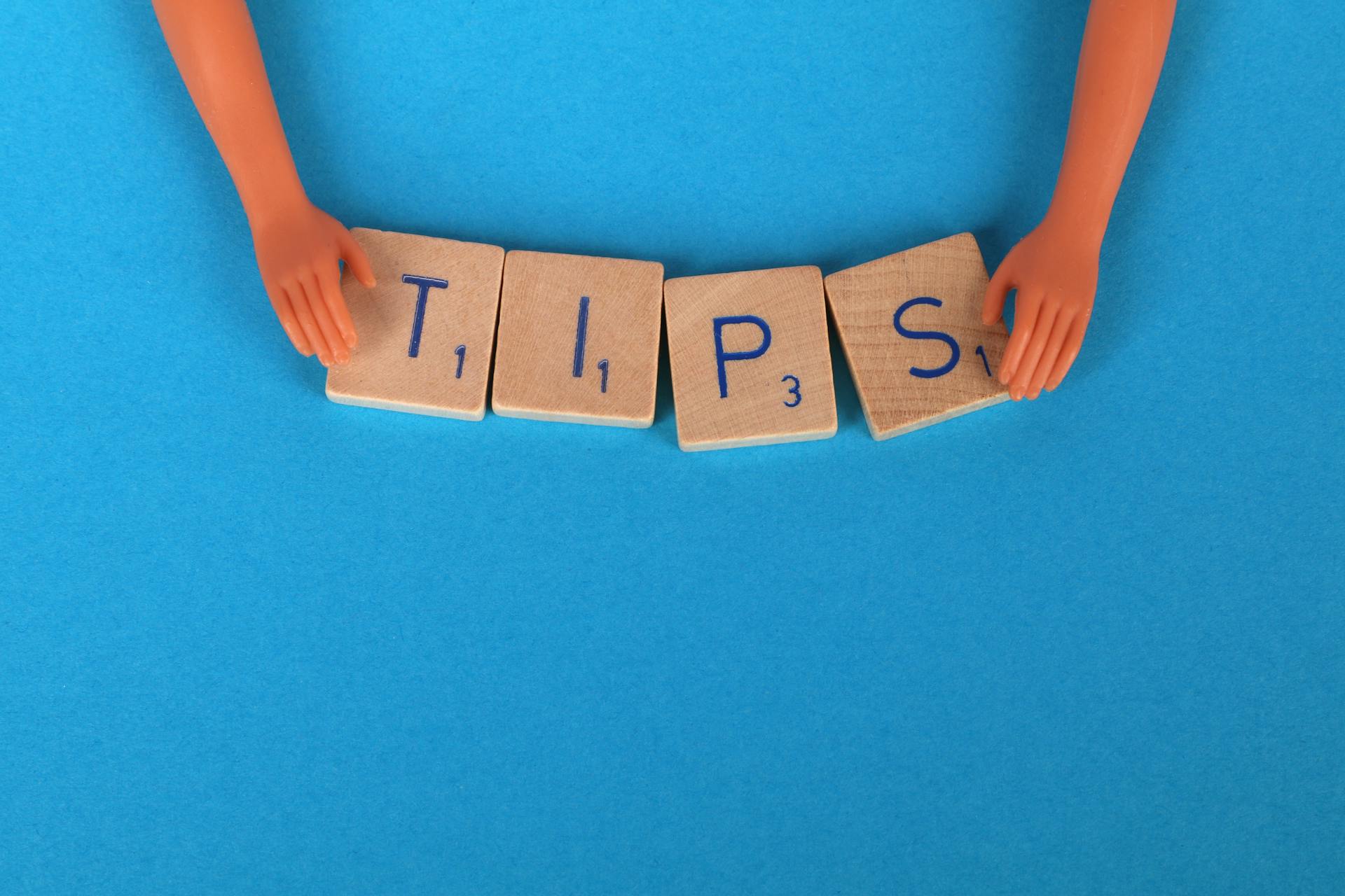 Small doll hands arrange Scrabble tiles to spell