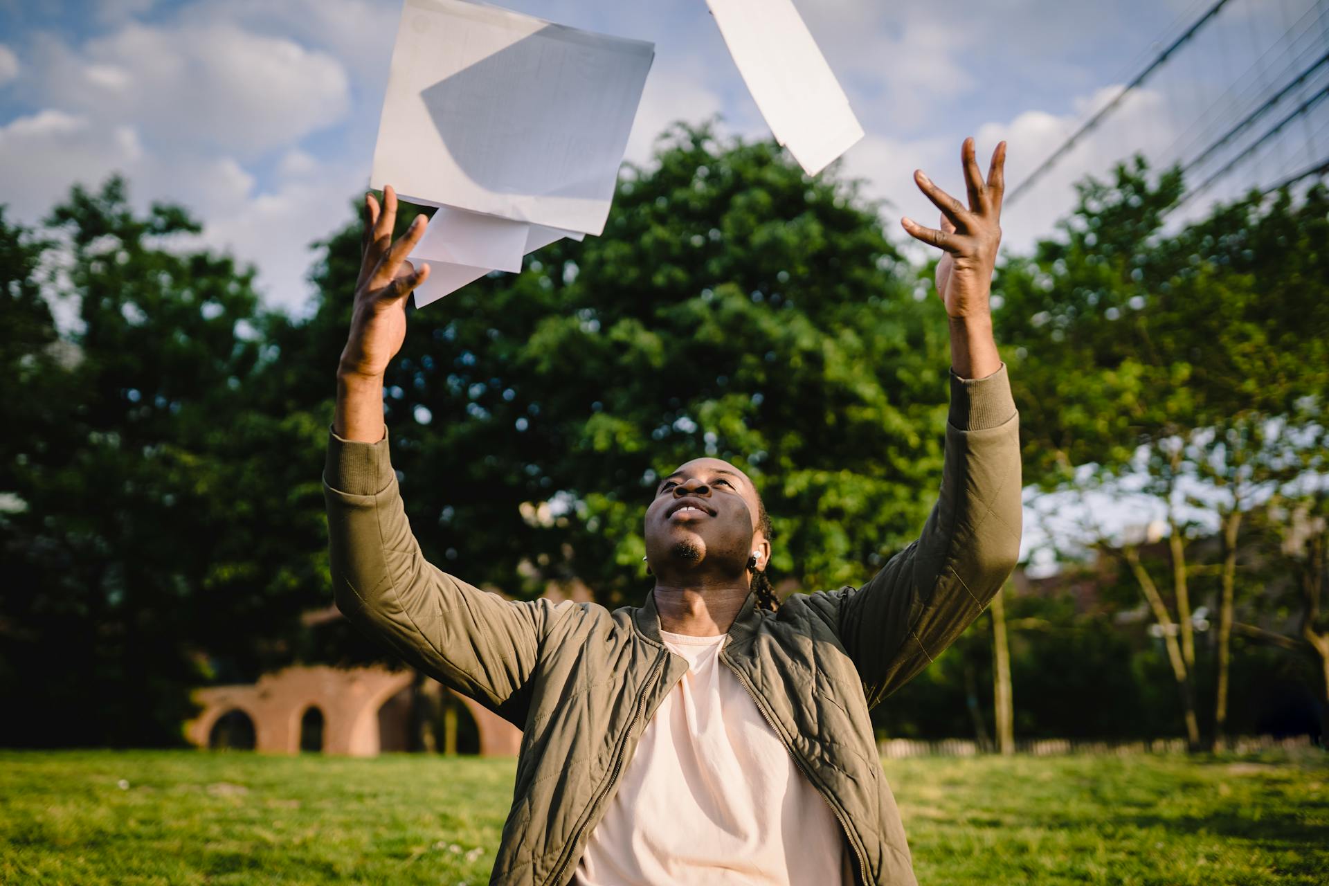 A smiling person throws paper in the air.
