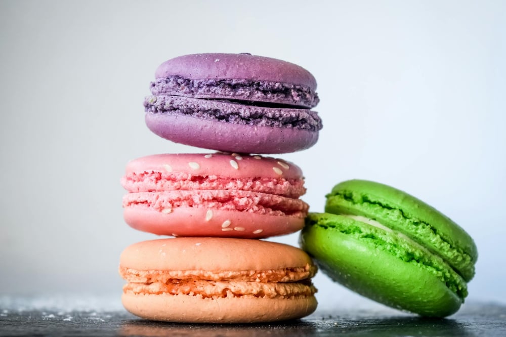 A stack of orange, pink, purple, and green macarons.