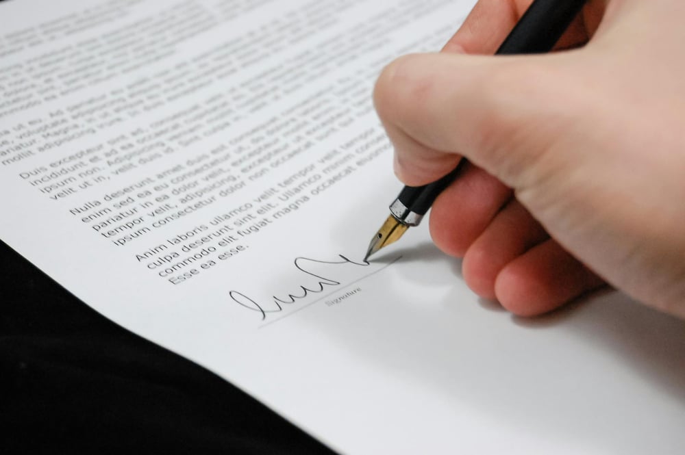A hand signs a contract.