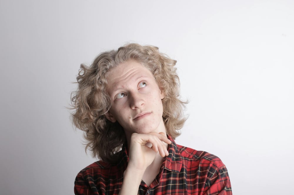 A person rests their head on their chin and looks off to the side, thinking.