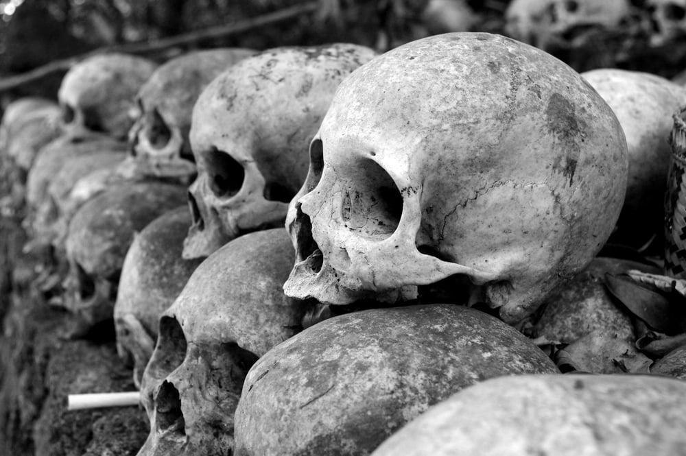 Human skulls piled on top of one another in neat lines.