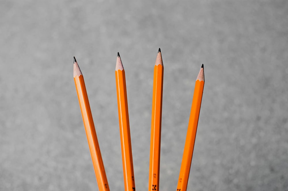 Four sharpened yellow pencils fanned out over a concrete background.