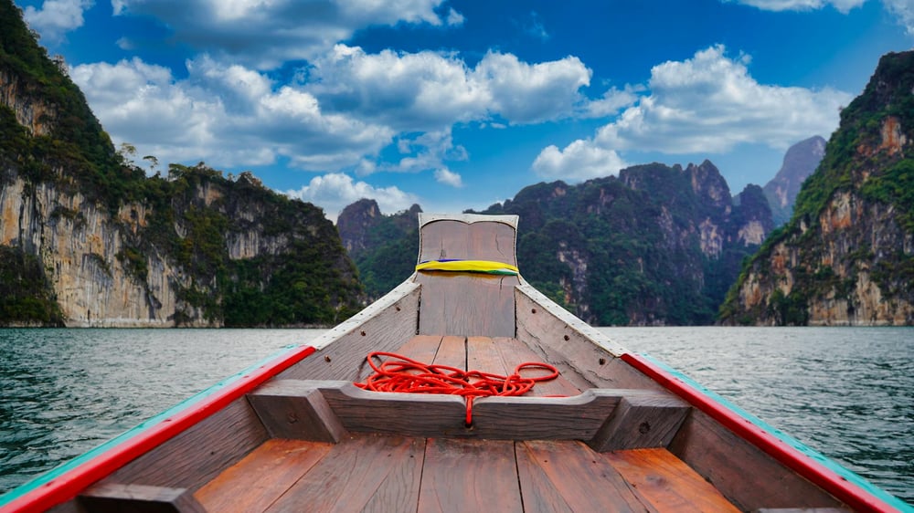 Beautiful green mountains rising up from the water seen from the perspective of the front seat of a boat.